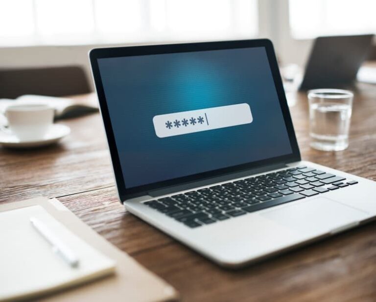 Laptop on a wooden desk showing a login screen