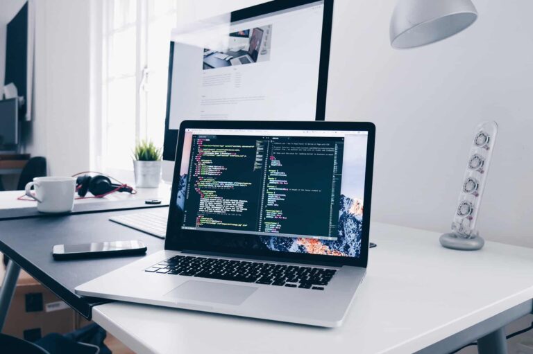 Laptop on a bright desk displaying lines of code