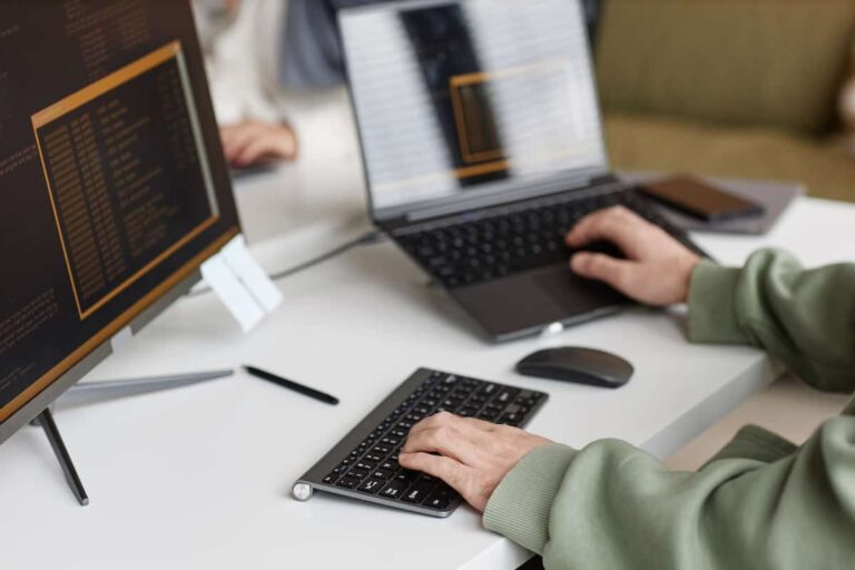 Person typing on a laptop and keyboard at a desk
