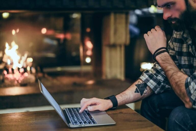 Person typing on a laptop in a dim cafe